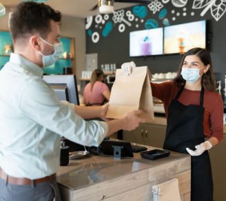 Restaurant employee handing out a takeout bag to a customer