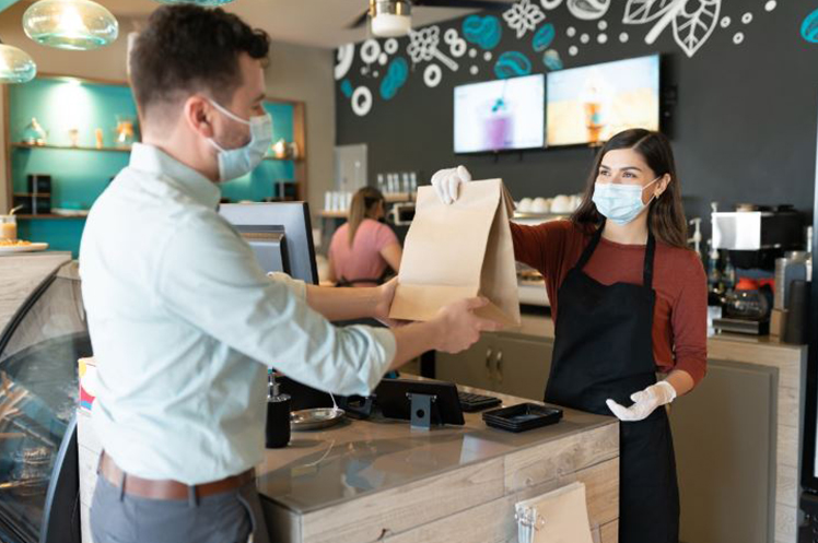 Restaurant employee handing out a takeout bag to a customer