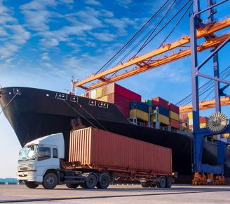 Shipping container on a semi-trailer truck beside a cargo ship