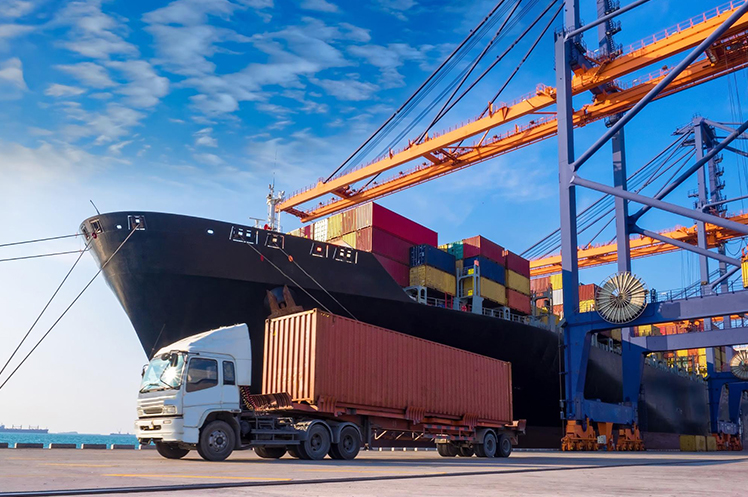 Shipping container on a semi-trailer truck beside a cargo ship