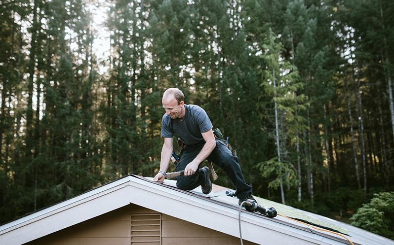 A roofing contractor installing tiles on a rooftop