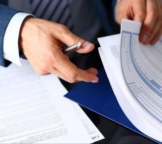 A closeup of a commercial property insurer’s hands as he flips through insurance papers