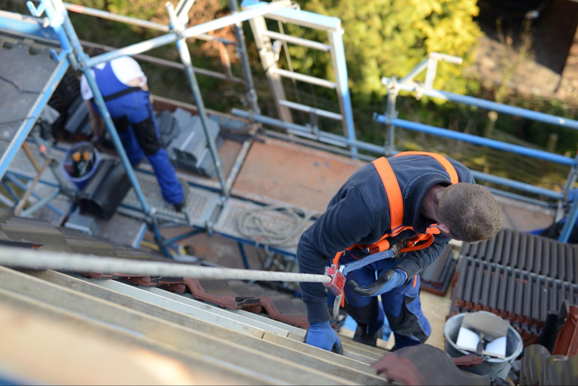 A roofing contractor on the roof with a safety harness