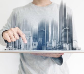 A man holding a tray of buildings, representing commercial properties in a city