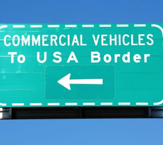 A sign saying “commercial vehicles to USA border,” directing cross border trucking efforts to the right lane