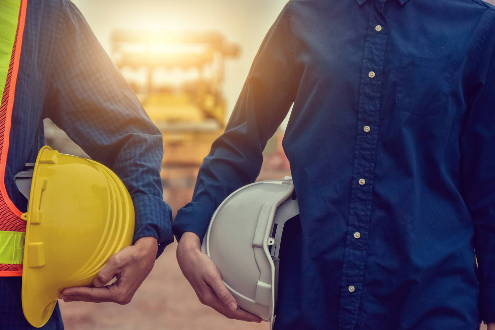 Two people holding construction helmets