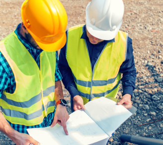 Two contractors reviewing blueprints at a construction site