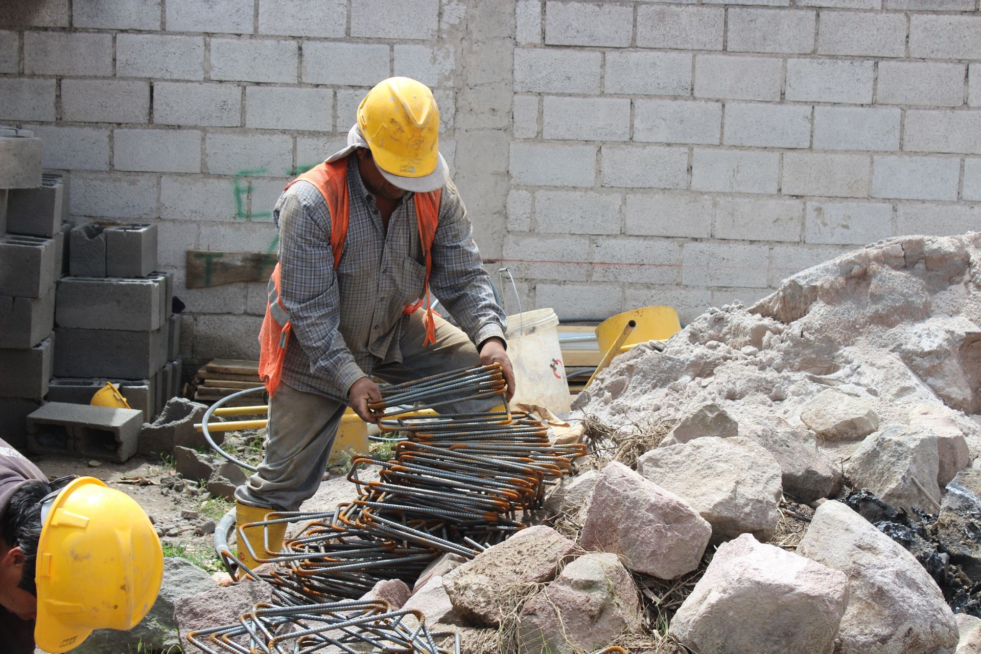 A construction worker gathering metal rods.