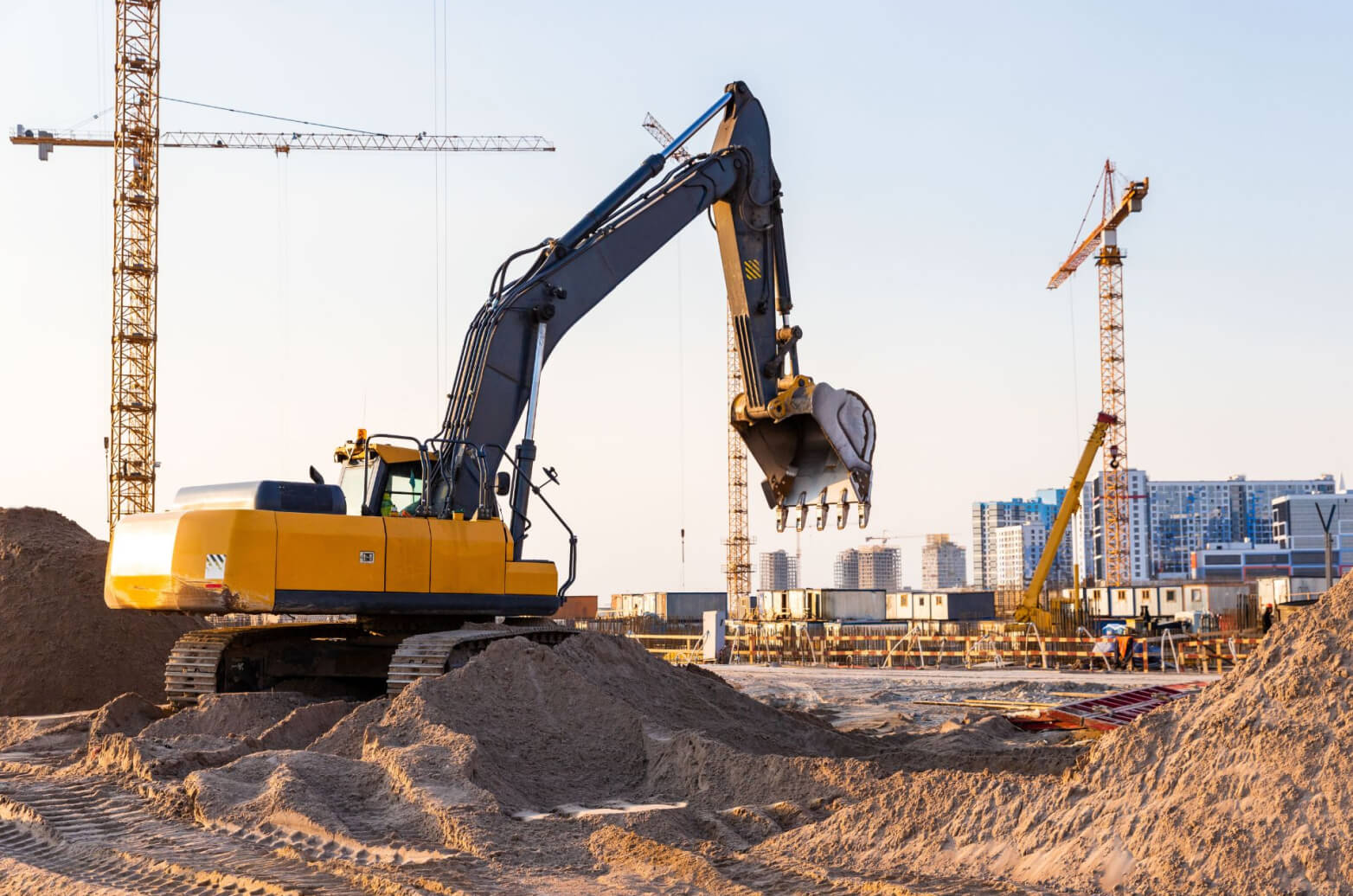 Cranes and an excavator in an industrial construction site