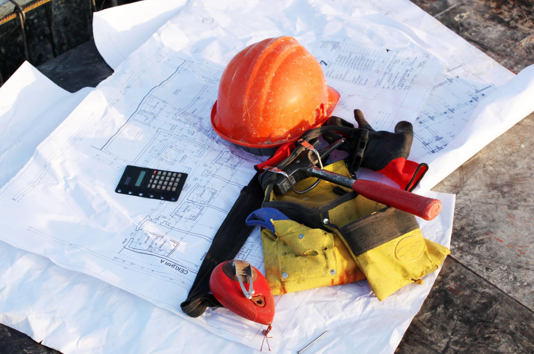 A contractor’s tools and equipment lying on top of blueprints
