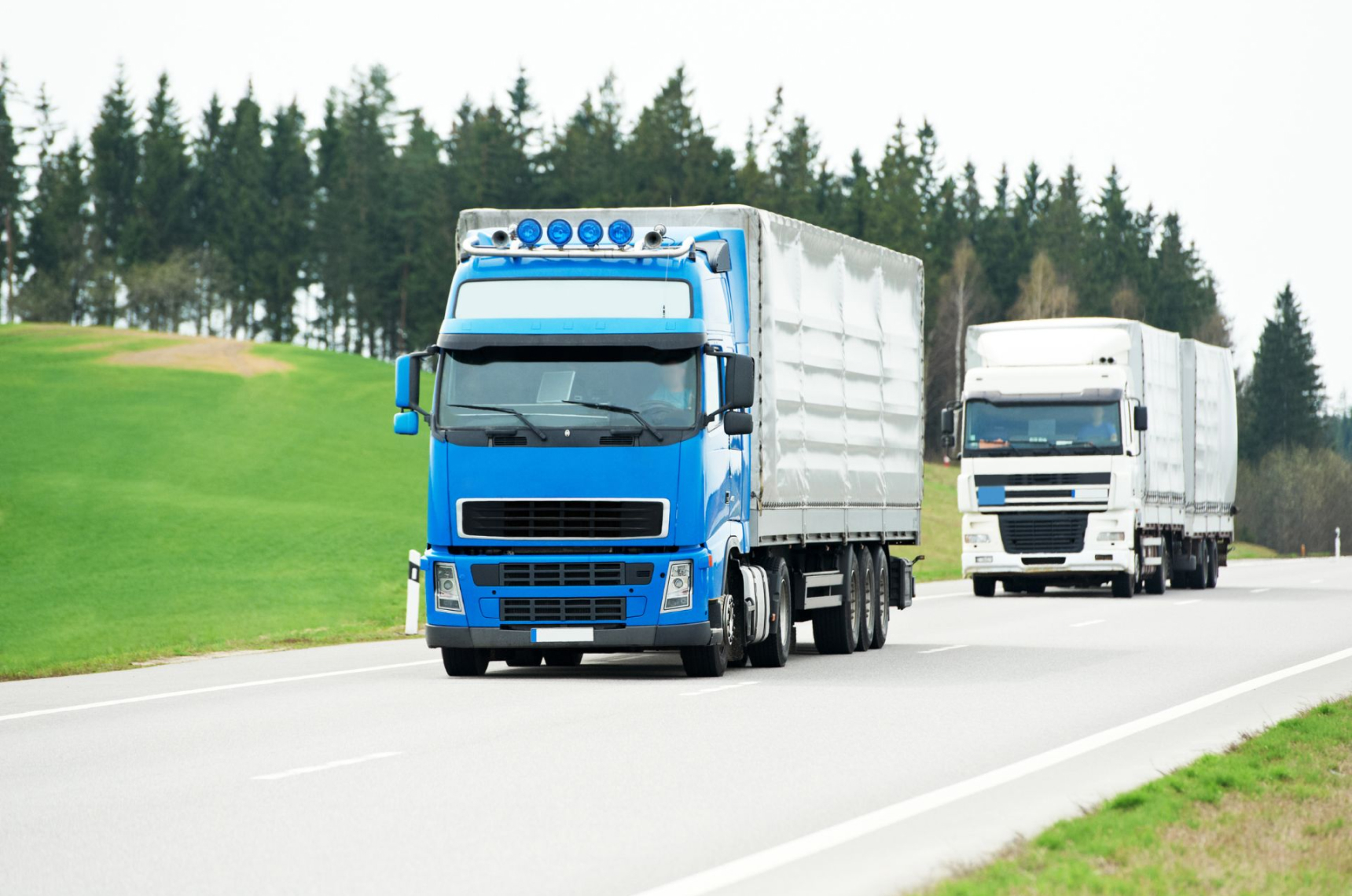 Two freight trucks driving down a highway
