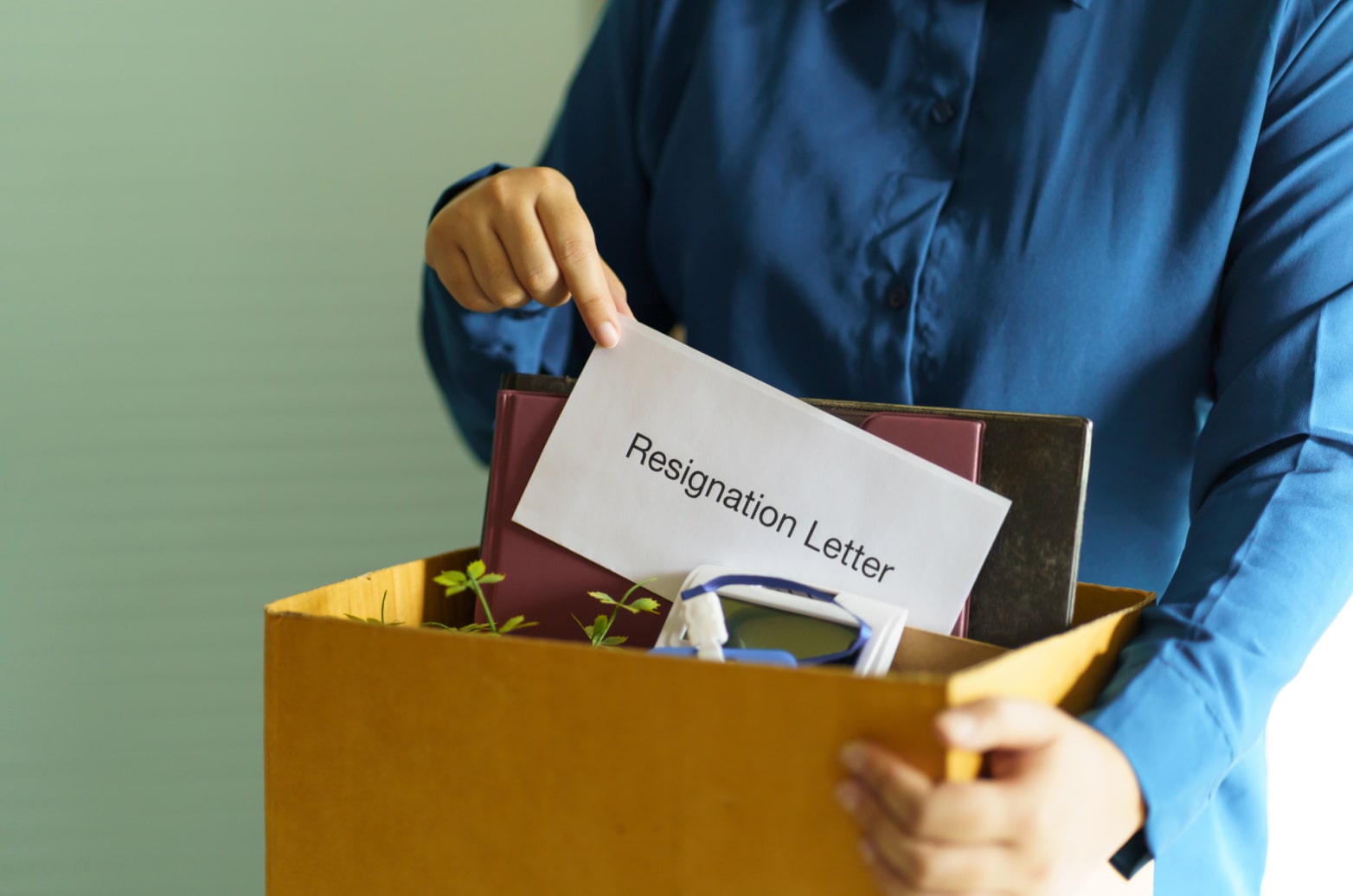 Someone pulling a resignation letter out of a box of office supplies