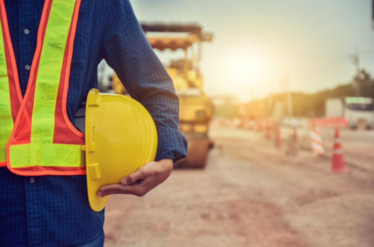 A contractor holds a hard hat by his side on a construction site