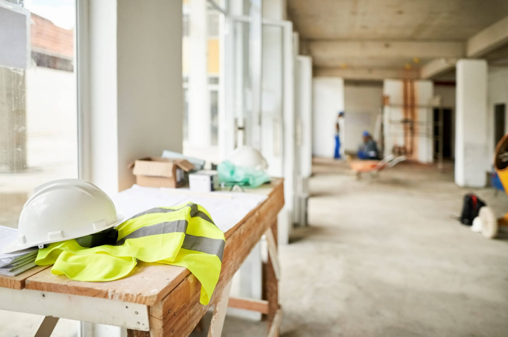 The interior of a construction site with a hard hat, vest, and tools on a workbench