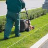 A landscape contractor mowing a narrow strip of grass