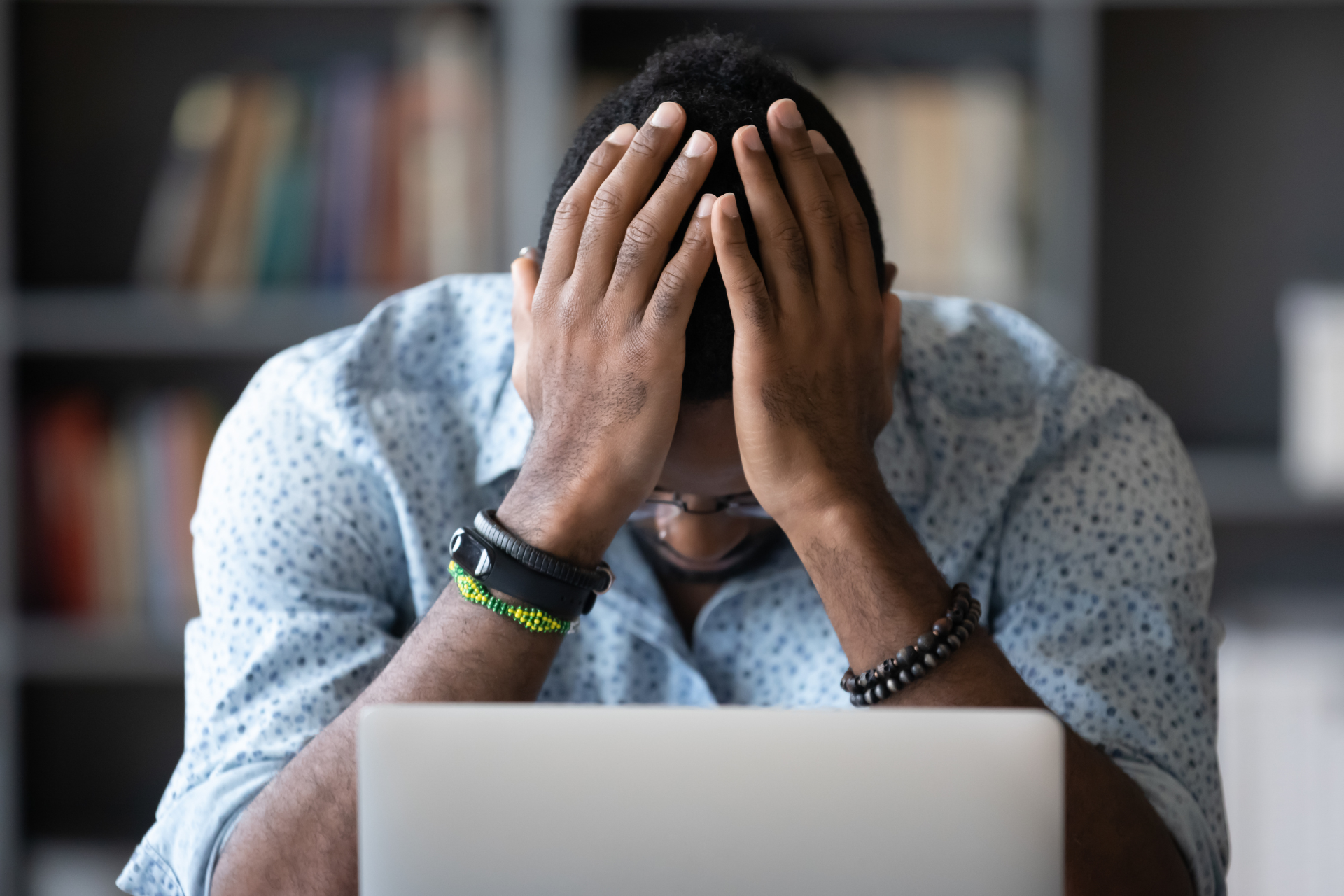 Person in front of a laptop with hands on his head