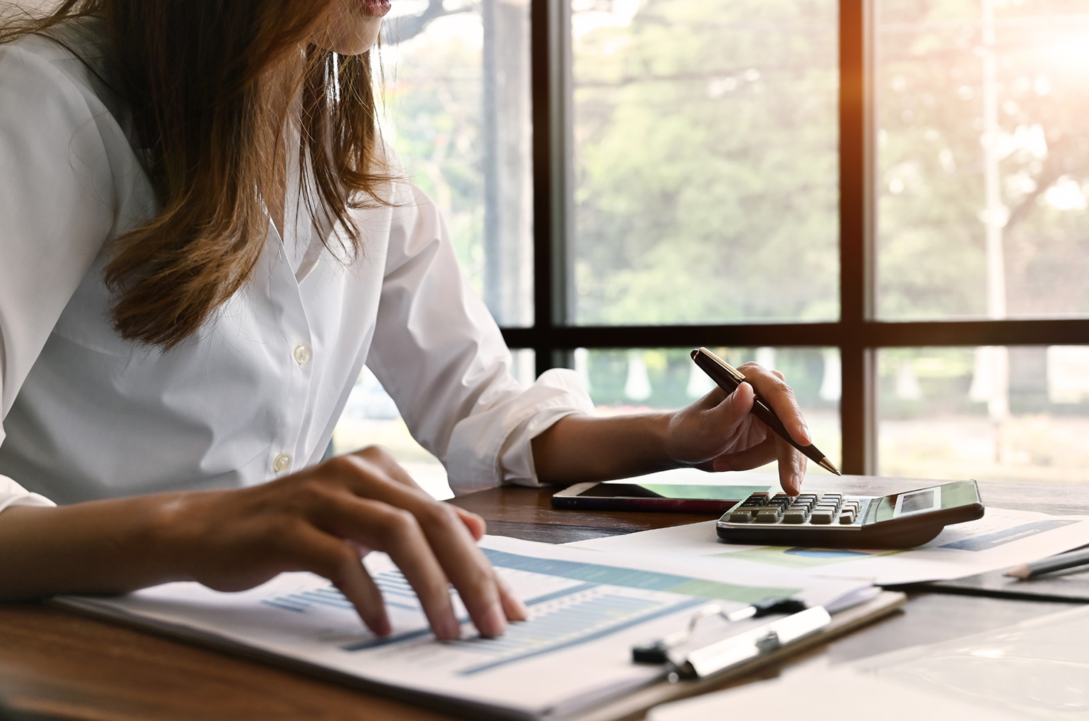 Accountant in a white blouse calculating business finances with a calculator