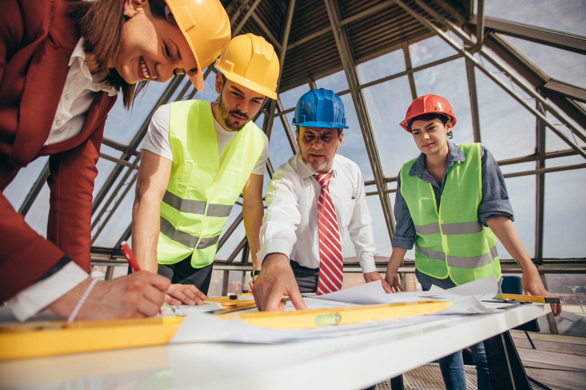 Four project shareholders wearing hard hats on a job site discussing construction plans