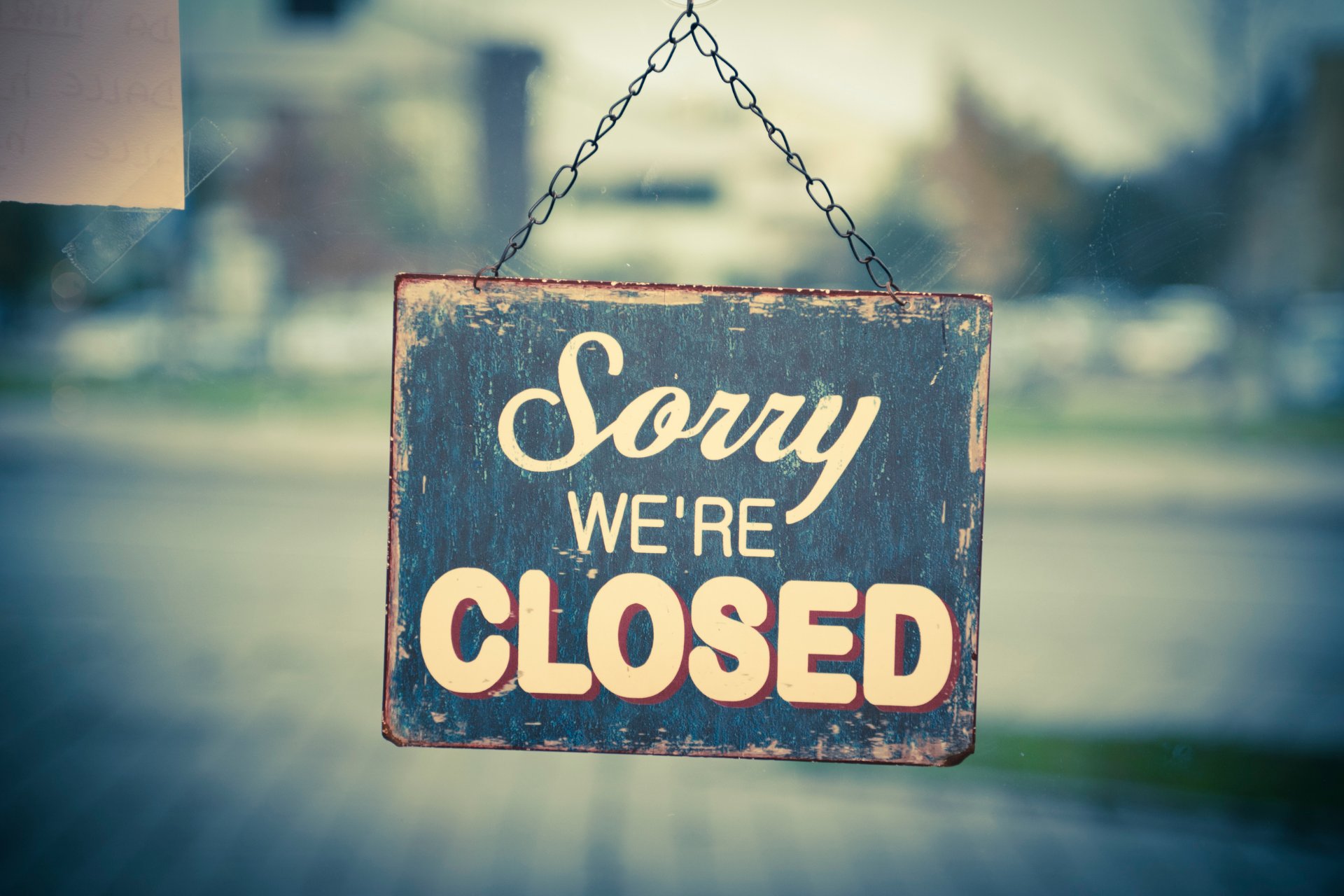 Sign reading “Sorry we’re closed” hanging on a glass door