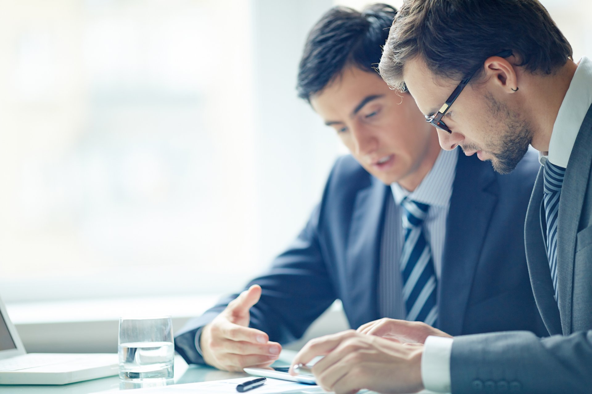 Two men in suits sitting at a table discussing how to mitigate risk in their business