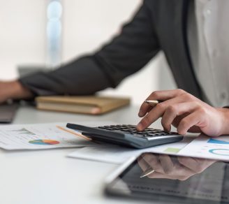 Businessman sitting at desk calculating accounts receivable on calculator