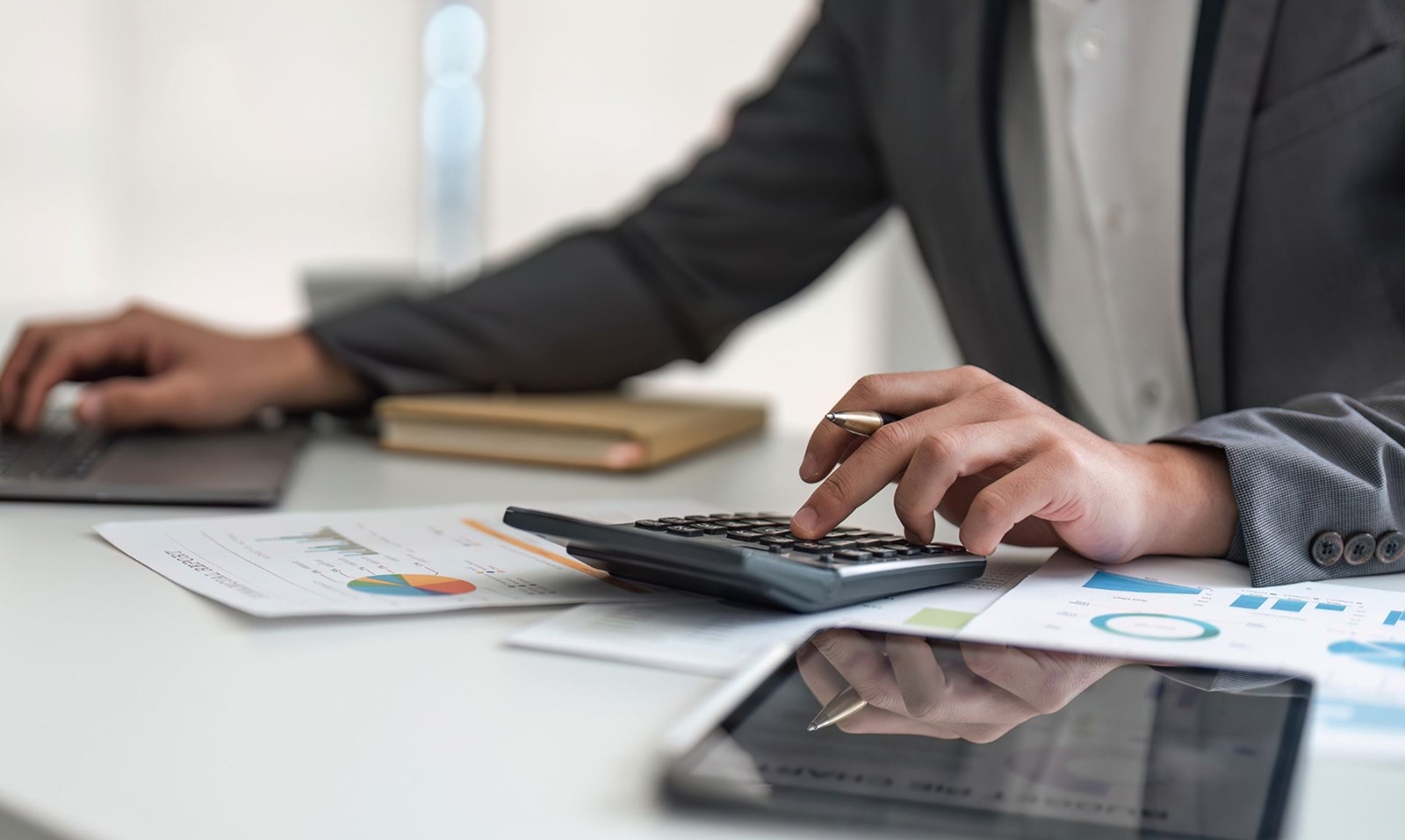 Businessman sitting at desk calculating accounts receivable on calculator