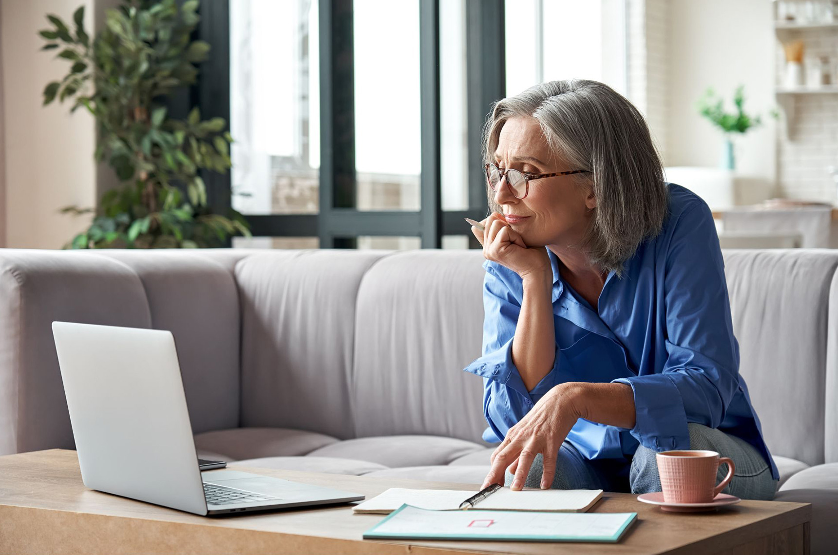 Businesswoman sitting on a coach working remotely from her laptop