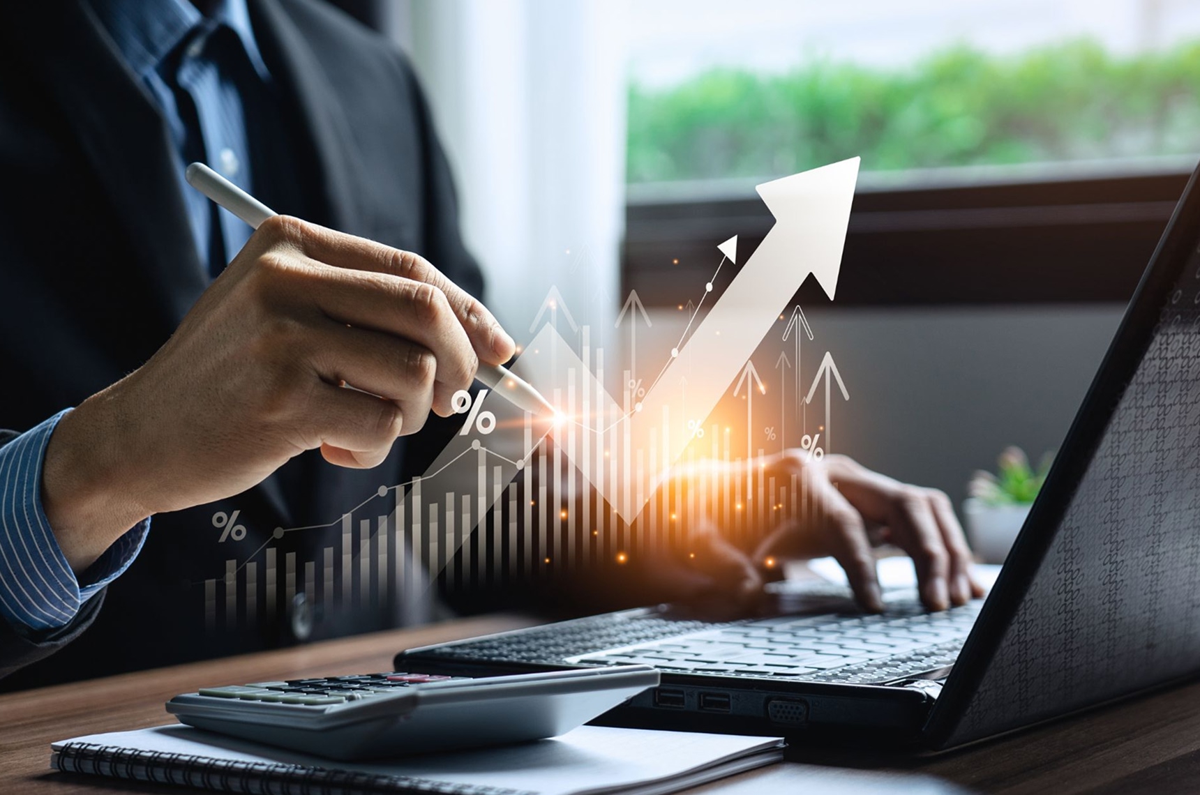 Business owner sitting at a desk with a laptop with a growth chart reflected