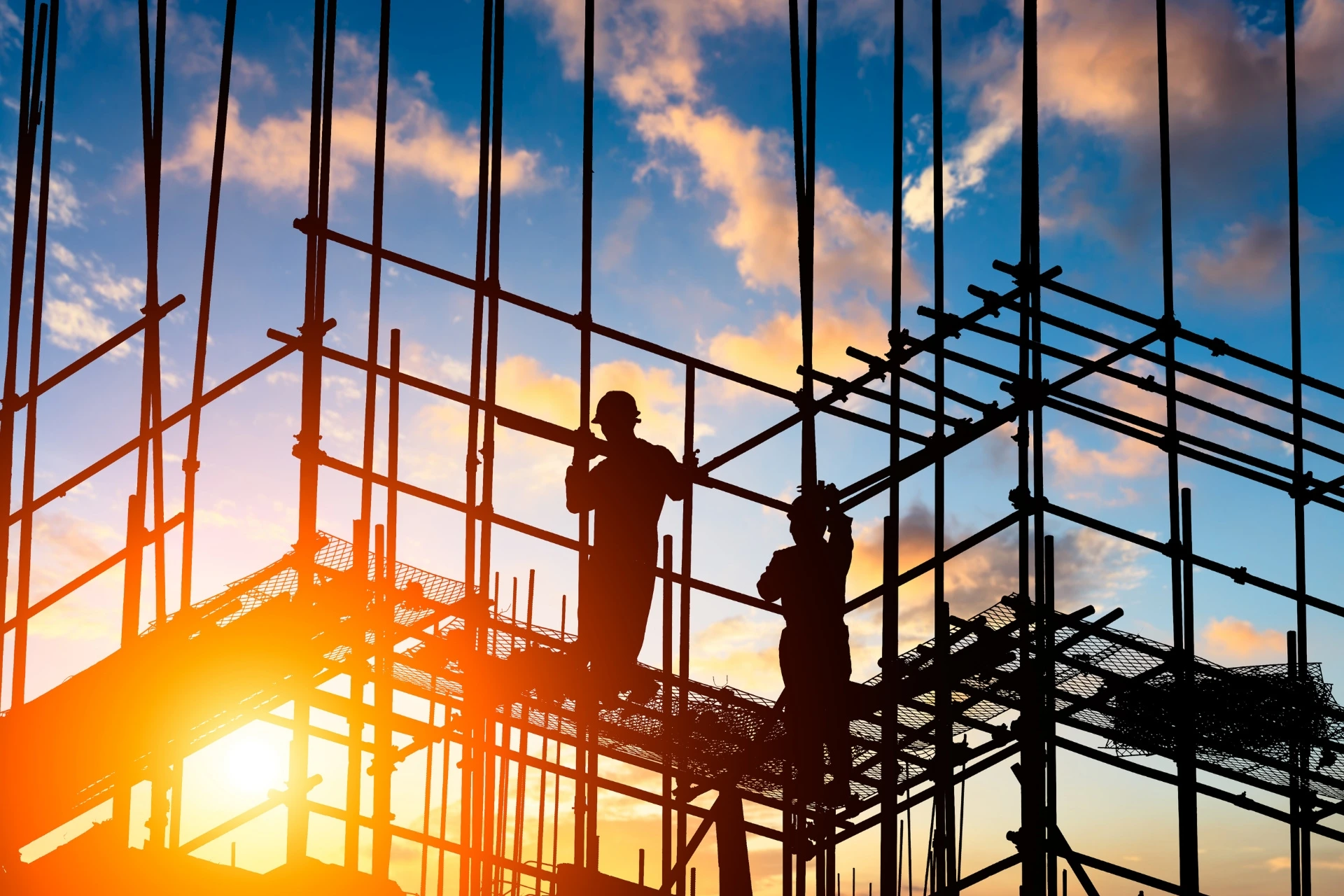 A construction crew stands on scaffolding on a job site.