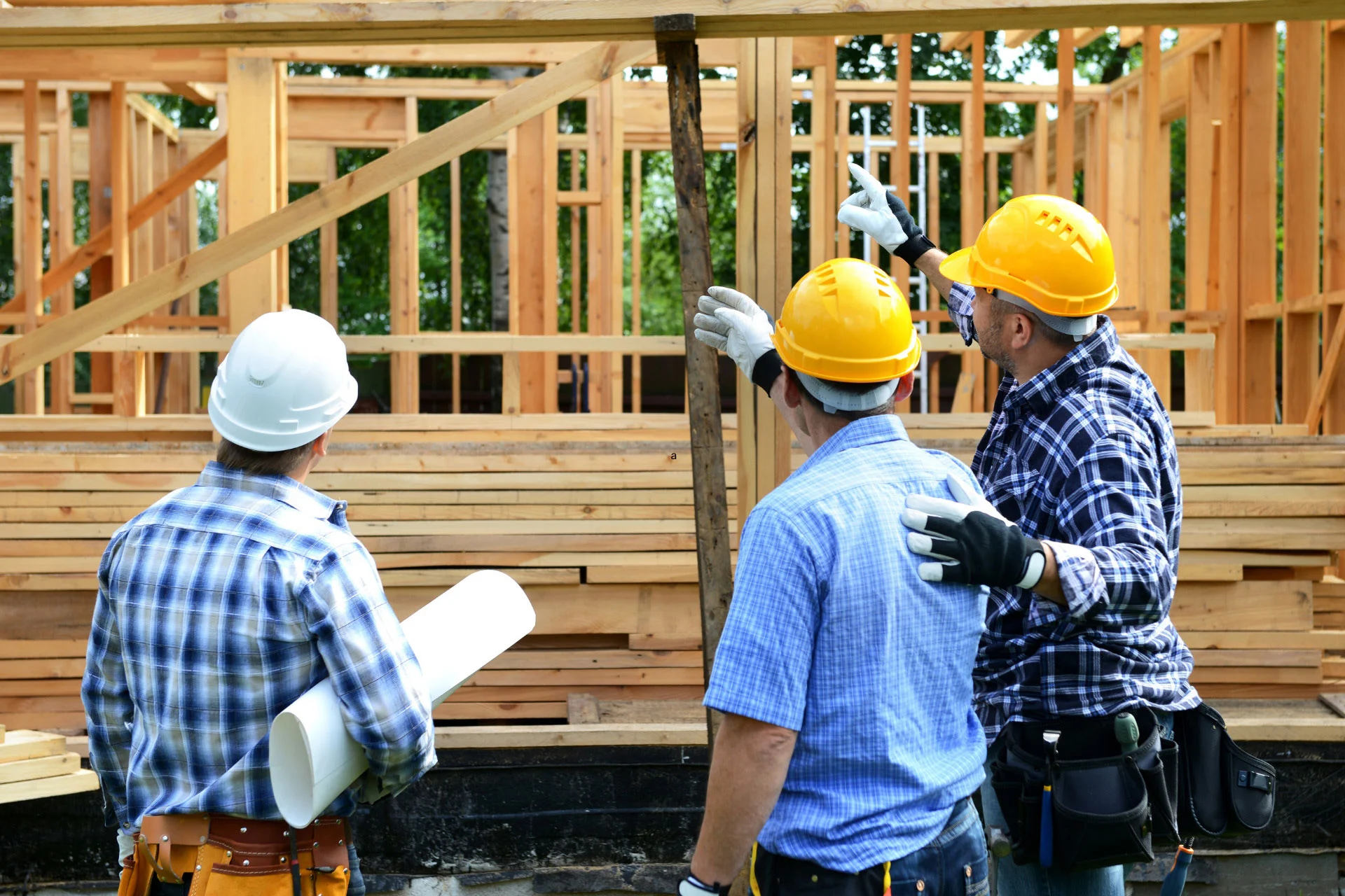 Three construction workers on the site of a home build.