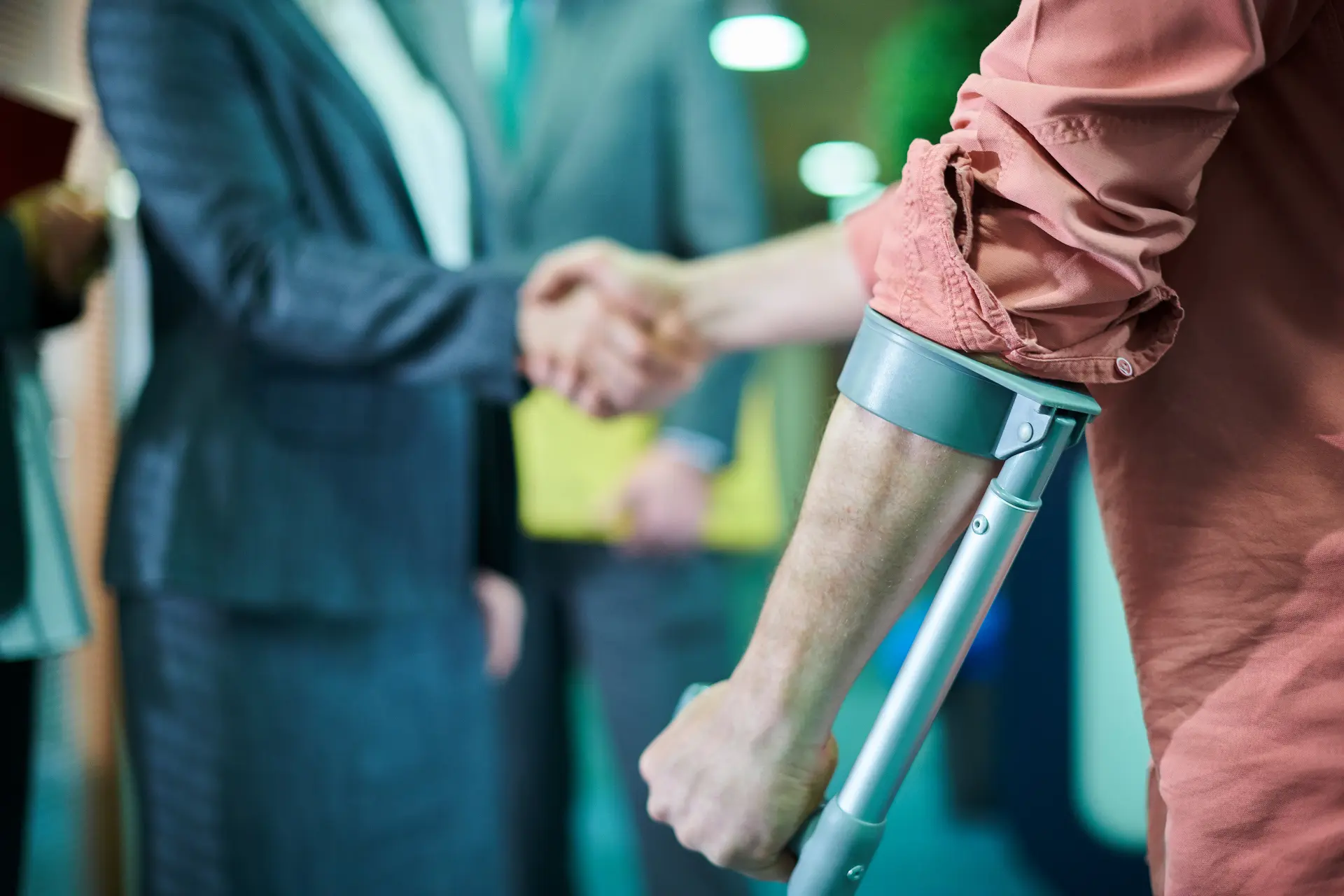  an injured employee wearing a forearm crutch shaking a woman’s hand in agreement

