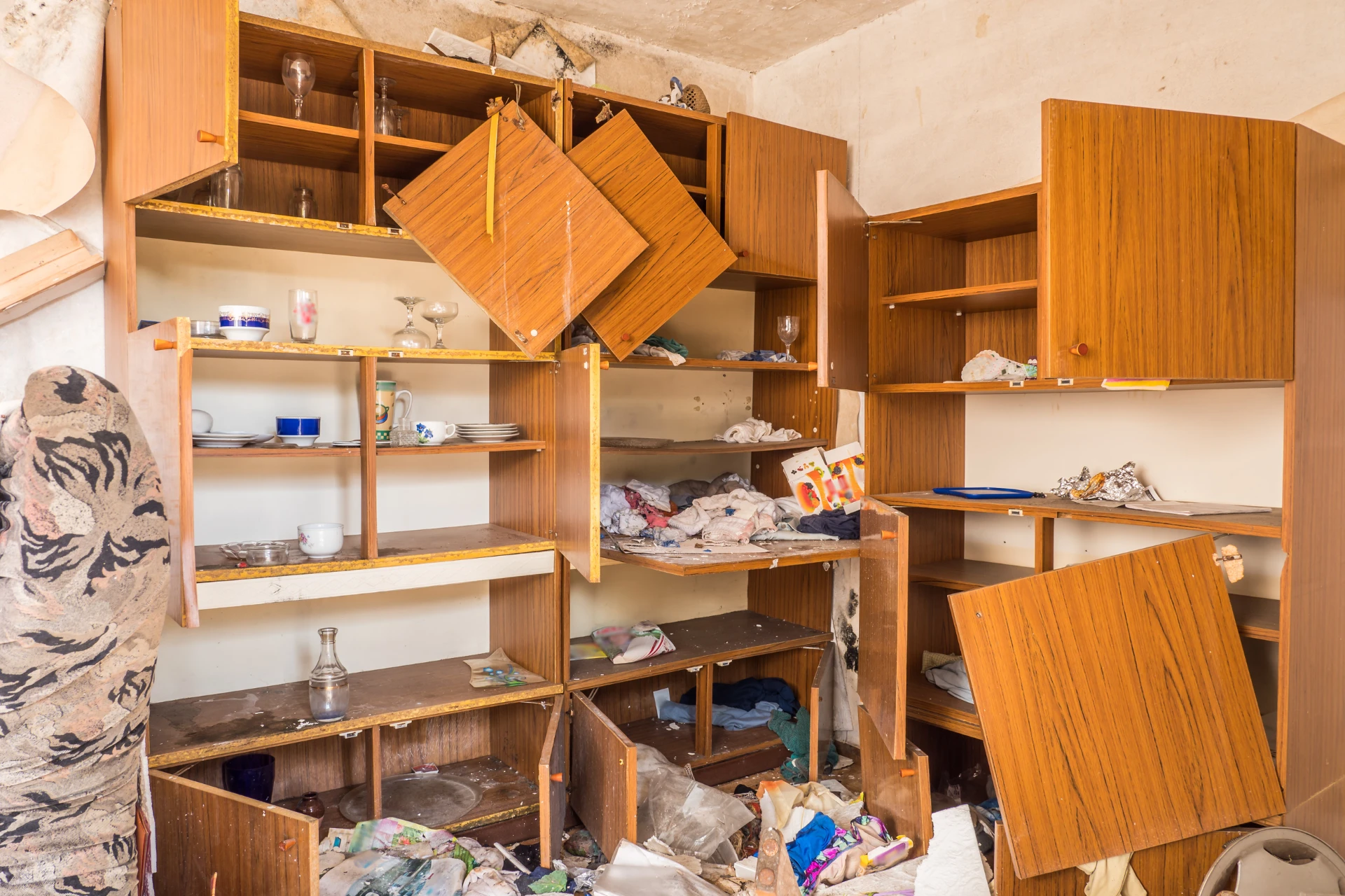 A vandalized space with cabinets torn from their places and garbage all over
