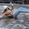 A woman in winter gear is slipping on an icy sidewalk
